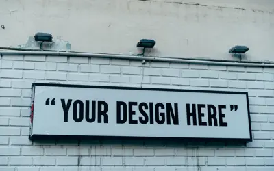 A sign on a brick wall that reads "Your Design Here"